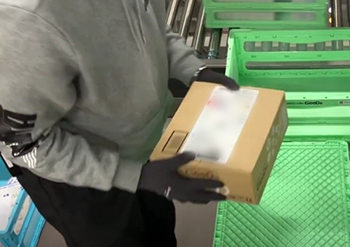 梱包完了後に箱を軽く振って商品の動きがないことを確認する品質チェック作業